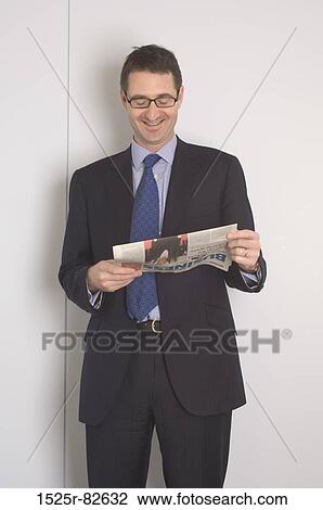 Businessman reading a newspaper and smiling View Large Photo Image Stock Image - Businessman reading a newspaper and smiling. Fotosearch