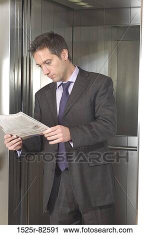 Businessman reading a newspaper in an elevator View Large Photo Image Stock Image - Businessman reading a newspaper in an elevator. Fotosearch