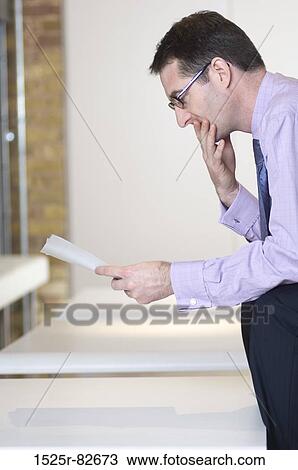 Businessman reading a paper View Large Photo Image Stock Image - Businessman reading a paper. Fotosearch