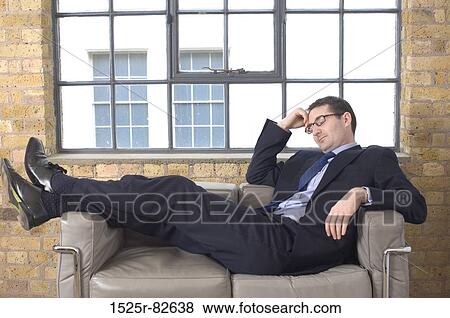 Businessman reclining on a couch View Large Photo Image Stock Photo - Businessman reclining on a couch. Fotosearch