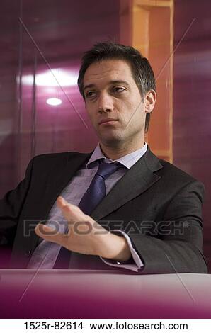 Picture - Businessman sitting at a table in an office. Fotosearch