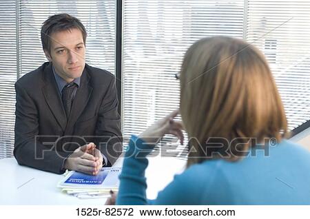Stock Image - Businessman sitting in front of a businesswoman. Fotosearch