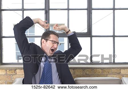 Businessman sitting on a couch and yawning View Large Photo Image Stock Image - Businessman sitting on a couch and yawning. Fotosearch