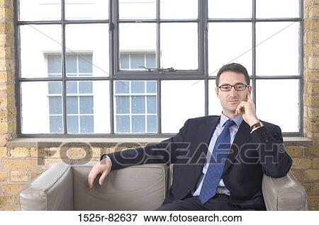 Businessman sitting on a couch and looking serious View Large Photo Image Stock Photo - Businessman sitting on a couch and looking serious. Fotosearch