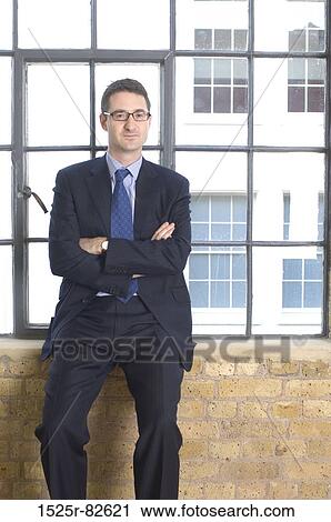 Businessman sitting on a window sill with his arms crossed View Large Photo Image Stock Image - Businessman sitting on a window sill with his arms crossed. Fotosearch