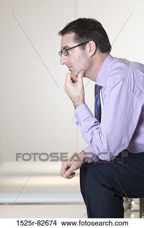 Businessman sitting with his hand on his chin View Large Photo Image Picture - Businessman sitting with his hand on his chin. Fotosearch