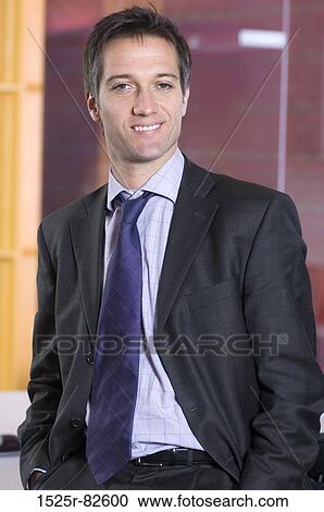 Businessman standing in an office and smiling View Large Photo Image Stock Image - Businessman standing in an office and smiling. Fotosearch