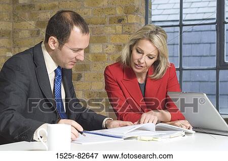 Businessman with a businesswoman looking at documents in an office View Large Photo Image Stock Photo - Businessman with a businesswoman looking at documents in an office. Fotosearch