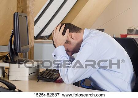 Businessman with his head in his hands sitting in front of a desktop PC View Large Photo Image Stock Photo - Businessman with his head in his hands sitting in front of a desktop PC. Fotosearch