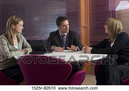 Businessman with two businesswomen talking in an office View Large Photo Image Stock Image - Businessman with two businesswomen talking in an office. Fotosearch