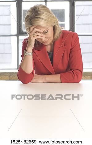 Businesswoman sitting at a table and looking depressed View Large Photo Image Stock Photo - Businesswoman sitting at a table and looking depressed. Fotosearch