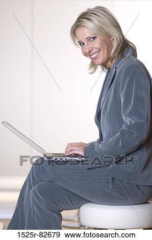 Businesswoman working on a laptop and smiling View Large Photo Image Stock Photo - Businesswoman working on a laptop and smiling. Fotosearch
