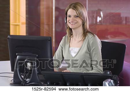 Female customer service representative sitting in front of a computer and smiling View Large Photo Image Picture - Female customer service representative sitting in front of a computer and smiling. Fotosearch