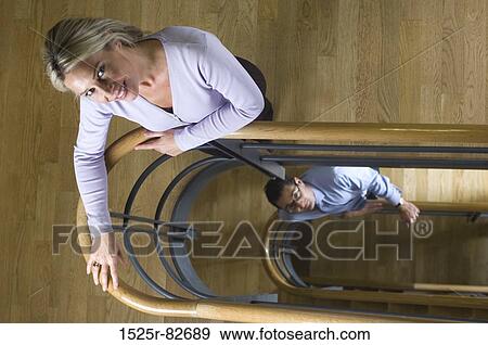 High angle view of a businesswoman and a businessman leaning against a hand rail and smiling View Large Photo Image Stock Photo - High angle view of a businesswoman and a businessman leaning against a hand rail and smiling. Fotosearch