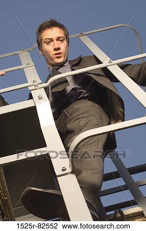 Low angle view of a businessman climbing up a ladder View Large Photo Image Stock Image - Low angle view of a businessman climbing up a ladder. Fotosearch