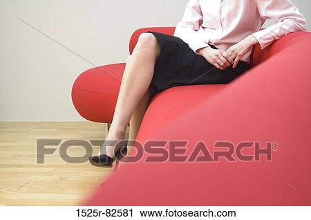 Low section view of a mid adult woman sitting on a couch View Large Photo Image Stock Image - Low section view of a mid adult woman sitting on a couch. Fotosearch