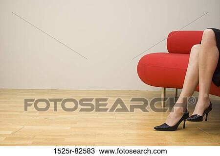Low section view of a mid adult woman sitting on a couch View Large Photo Image Stock Image - Low section view of a mid adult woman sitting on a couch. Fotosearch