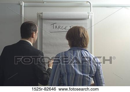 Rear view of a businessman with a businesswoman standing in front of a chart View Large Photo Image Stock Photograph - Rear view of a businessman with a businesswoman standing in front of a chart. Fotosearch