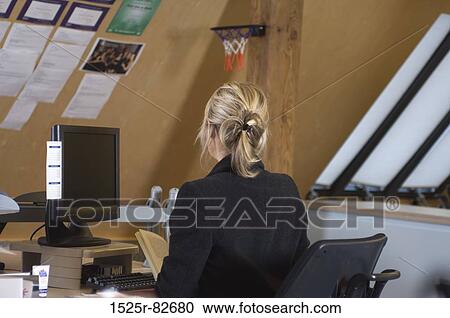 Rear view of a businesswoman sitting in front of a desktop PC View Large Photo Image Stock Image - Rear view of a businesswoman sitting in front of a desktop PC. Fotosearch