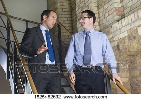 Two businessmen talking to each other on a staircase View Large Photo Image Stock Image - Two businessmen talking to each other on a staircase. Fotosearch