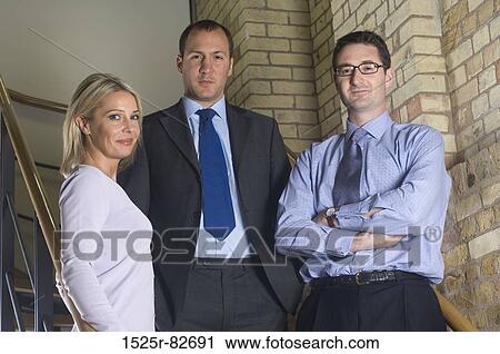 Two businessmen with a businesswoman standing on a staircase View Large Photo Image Stock Image - Two businessmen with a businesswoman standing on a staircase. Fotosearch