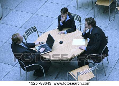 Stock Photo of two men and woman are sitting around a table discussing ...