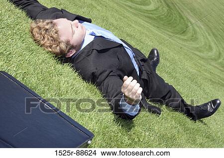 Business man has finally had it, collapses into relaxation on the green hill of tranquility View Large Photo Image Picture - Business man has finally had it, collapses into relaxation on the green hill of tranquility. Fotosearch