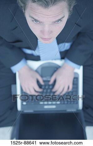 Business man in dark blue suit, blue shirt, and blue tie is typing on his laptop and is looking up View Large Photo Image Stock Image - Business man in dark blue suit, blue shirt, and blue tie is typing on his laptop and is looking up. Fotosearch
