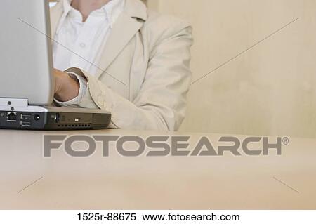 Business woman in tan jacket is busily typing on her laptop, which is on a table in an office building View Large Photo Image Stock Photography - Business woman in tan jacket is busily typing on her laptop, which is on a table in an office building. Fotosearch
