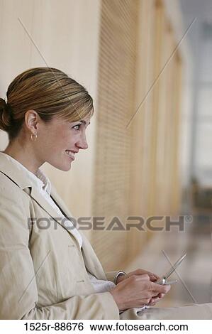 Business woman wearing tan jacket is standing against a wall View Large Photo Image Stock Photograph - Business woman wearing tan jacket is standing against a wall. Fotosearch
