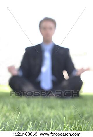 Businessman in black suit is meditating in the green grass with the sun behind him View Large Photo Image Stock Image - Businessman in black suit is meditating in the green grass with the sun behind him. Fotosearch