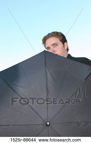 Businessman is holding umbrella with only his face showing View Large Photo Image Picture - Businessman is holding umbrella with only his face showing. Fotosearch