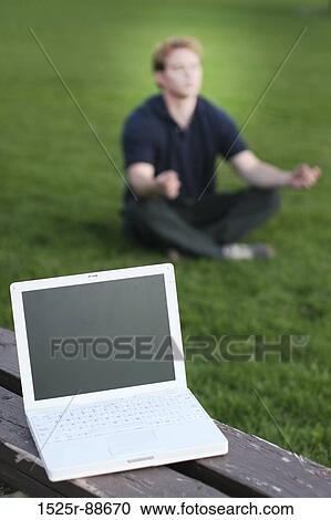 Businessman is meditating in the green grass as his white laptop sits on the brown bench View Large Photo Image Stock Image - Businessman is meditating in the green grass as his white laptop sits on the brown bench. Fotosearch