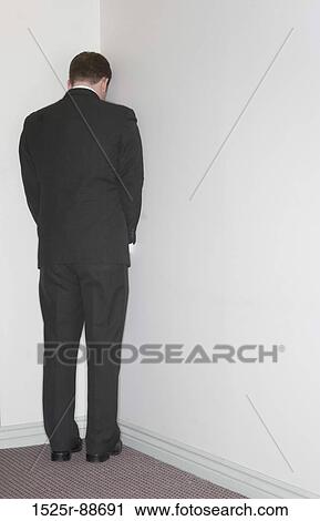 Businessman stands in the corner against a white wall in the office View Large Photo Image Stock Image - Businessman stands in the corner against a white wall in the office. Fotosearch