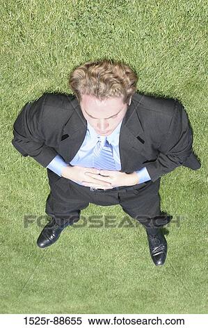 Businessman wearing black suit and blue shirt is completely sprawled out on the green grass View Large Photo Image Stock Photography - Businessman wearing black suit and blue shirt is completely sprawled out on the green grass. Fotosearch