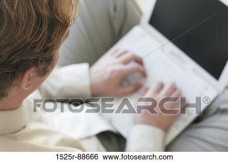 Businessman with brown hair and tan shirt is typing on his white laptop View Large Photo Image Stock Photograph - Businessman with brown hair and tan shirt is typing on his white laptop. Fotosearch