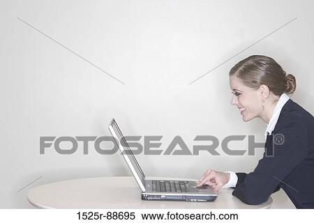 Stock Photography - Businesswoman sitting at her table with her laptop using her technology. Fotosearch