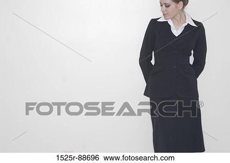 businesswoman standing alone against a white wall with her hands behind her looking down View Large Photo Image Stock Photograph - businesswoman standing alone against a white wall with her hands behind her looking down. Fotosearch