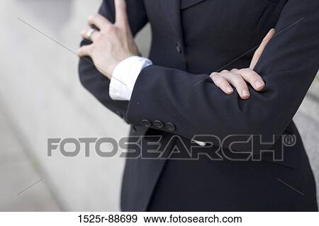 Businesswoman standing outside with her arms folded in front of her View Large Photo Image Stock Photo - Businesswoman standing outside with her arms folded in front of her. Fotosearch