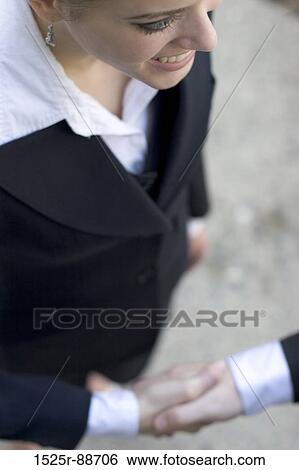 Businesswoman standing with another businessman giving a business handshake View Large Photo Image Stock Photograph - Businesswoman standing with another businessman giving a business handshake. Fotosearch