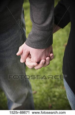 Couple holding hands wearing jeans in the green grass View Large Photo Image Stock Image - Couple holding hands wearing jeans in the green grass. Fotosearch
