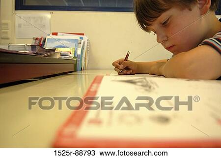 Stock Image - Boy studying at a table. Fotosearch