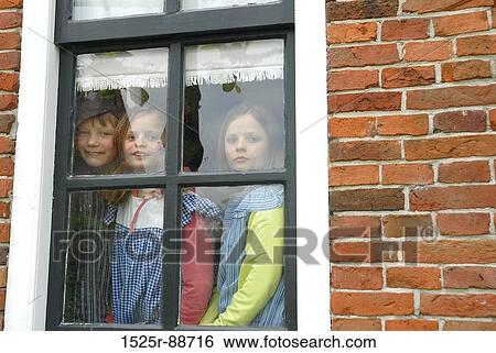 Boy with his two sisters looking through a window View Large Photo Image Stock Photograph - Boy with his two sisters looking through a window. Fotosearch