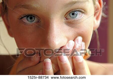 Picture - Close-up of a girl covering her mouth with her hands. Fotosearch