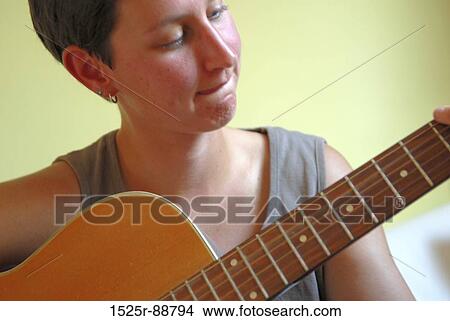 Close-up of a mid adult woman playing a guitar View Large Photo Image Picture - Close-up of a mid adult woman playing a guitar. Fotosearch