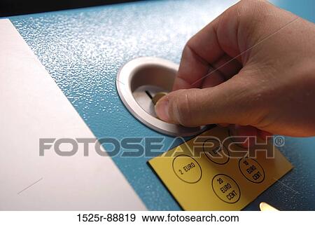Stock Photo - Close-up of a person's hand inserting a coin into a coin operated machine. Fotosearch