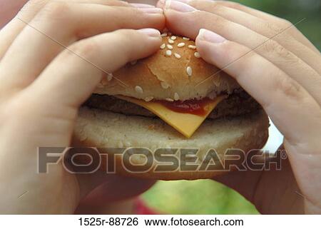 Close-up of a person's hands holding a cheeseburger View Large Photo Image Stock Photograph - Close-up of a person's hands holding a cheeseburger. Fotosearch
