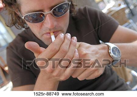 Close-up of a young man lighting a cigarette View Large Photo Image Stock Photo - Close-up of a young man lighting a cigarette. Fotosearch