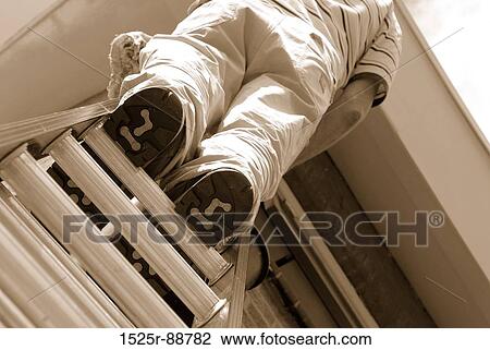 Low angle view of a man standing on a ladder View Large Photo Image Stock Image - Low angle view of a man standing on a ladder. Fotosearch