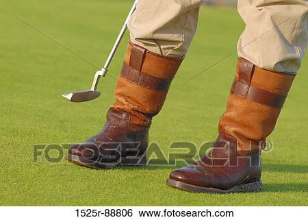 Low section view of a person standing with a golf club View Large Photo Image Stock Photograph - Low section view of a person standing with a golf club. Fotosearch